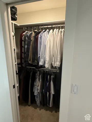 Reach-in closet featuring dual-tier metal hanging rods and white built-in shelving