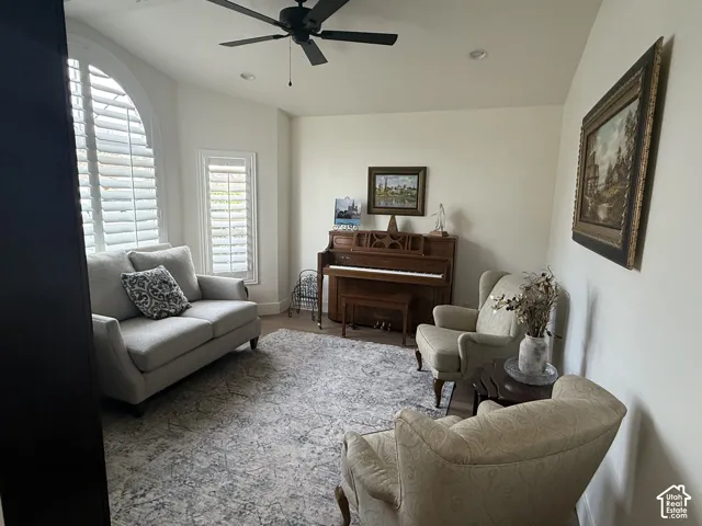 Arched window featuring white plantation shutters, vaulted ceiling, and matte black ceiling fan