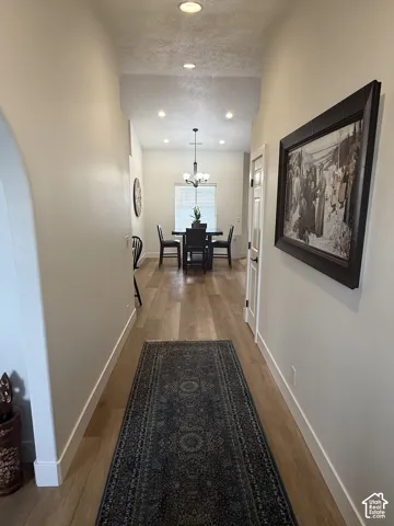 Hallway featuring wood-finish flooring, an arched entryway, and recessed lighting