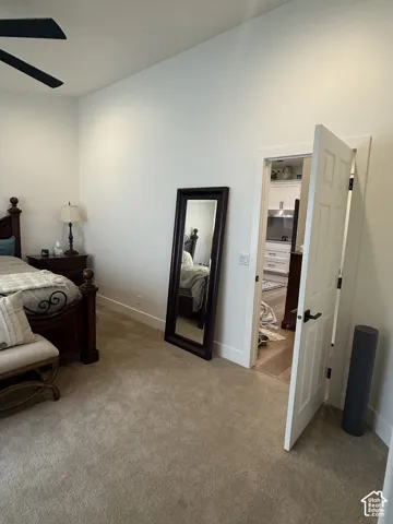 High-ceilinged room featuring carpeted flooring, a ceiling fan, and a six-panel interior door with matte black hardware
