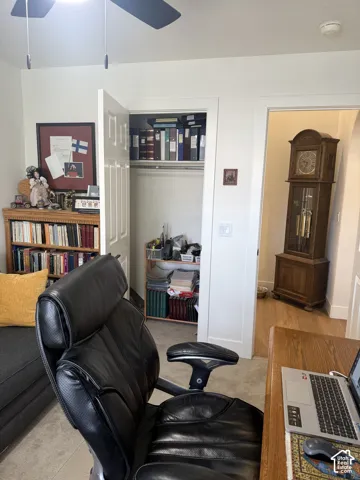 Interior room featuring a ceiling-mounted fan, neutral carpeting, and a reach-in closet with built-in shelving