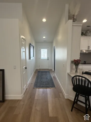 Entryway featuring vaulted ceilings, recessed lighting, wood-finish flooring, a paneled door with glass insert, and an arched entryway