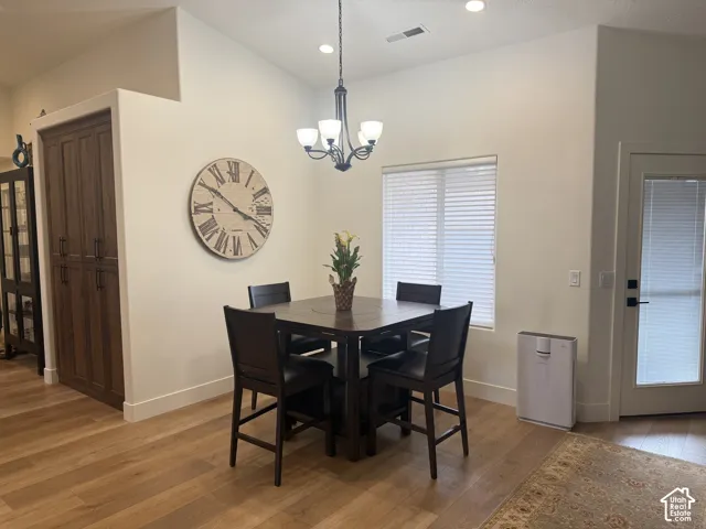 Vaulted ceiling, wood-finish flooring, built-in floor-to-ceiling cabinetry, multi-light chandelier, and glass-paneled exterior door