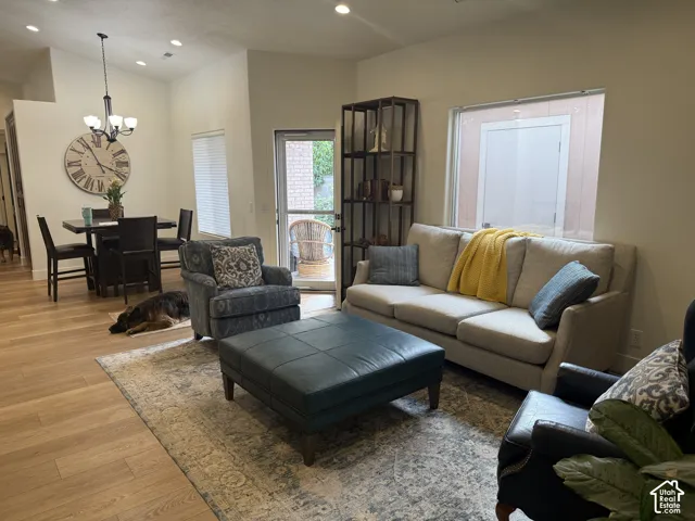 Open-concept interior featuring wood-finish flooring, recessed lighting, vaulted ceilings, and a multi-light chandelier