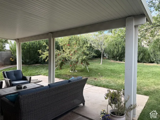 Covered patio featuring a solid ceiling and support columns, concrete flooring, and a fenced backyard with a lawn and mature trees