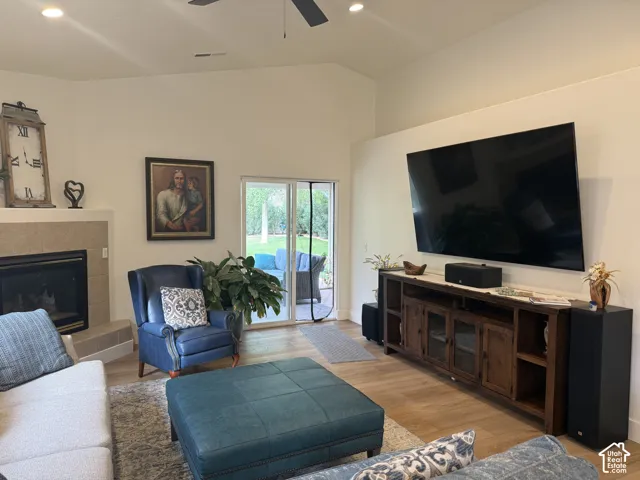 Vaulted ceilings with recessed lighting, tile-surround fireplace, wood-finish flooring, and glass sliding door