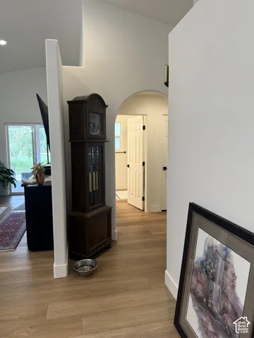 Interior featuring wood-finish flooring, vaulted ceilings, and a structural archway