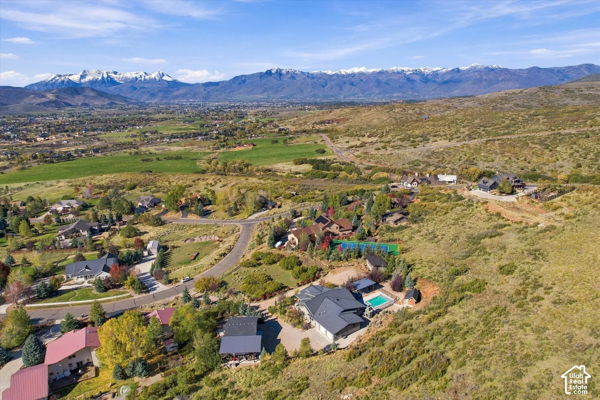 Aerial perspective of property featuring an expansive multi-level residence, private swimming pool, mountain backdrop, and hillside landscaping