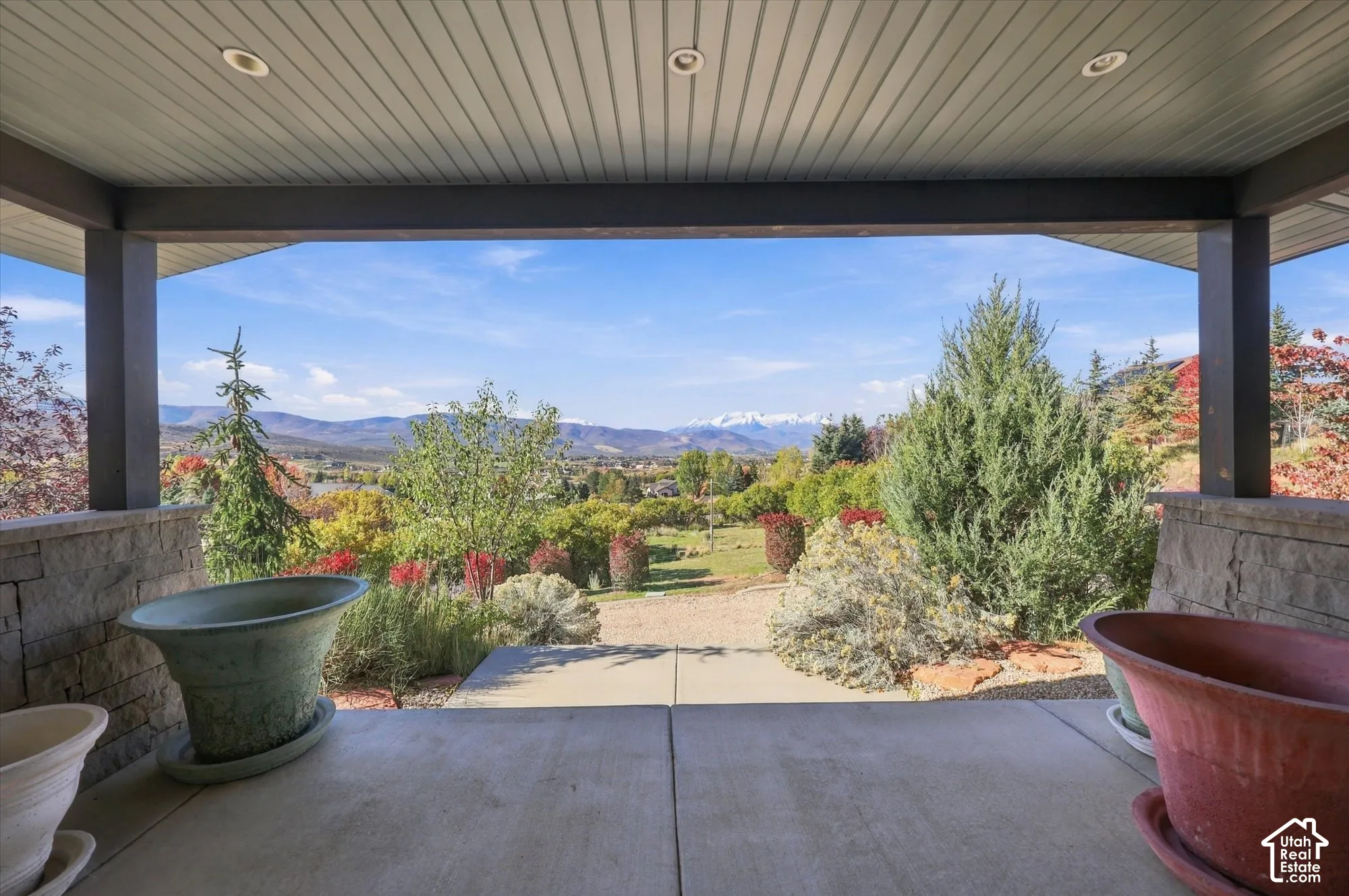 Covered concrete patio featuring stone-clad pillars, recessed lighting, and expansive mountain scenery
