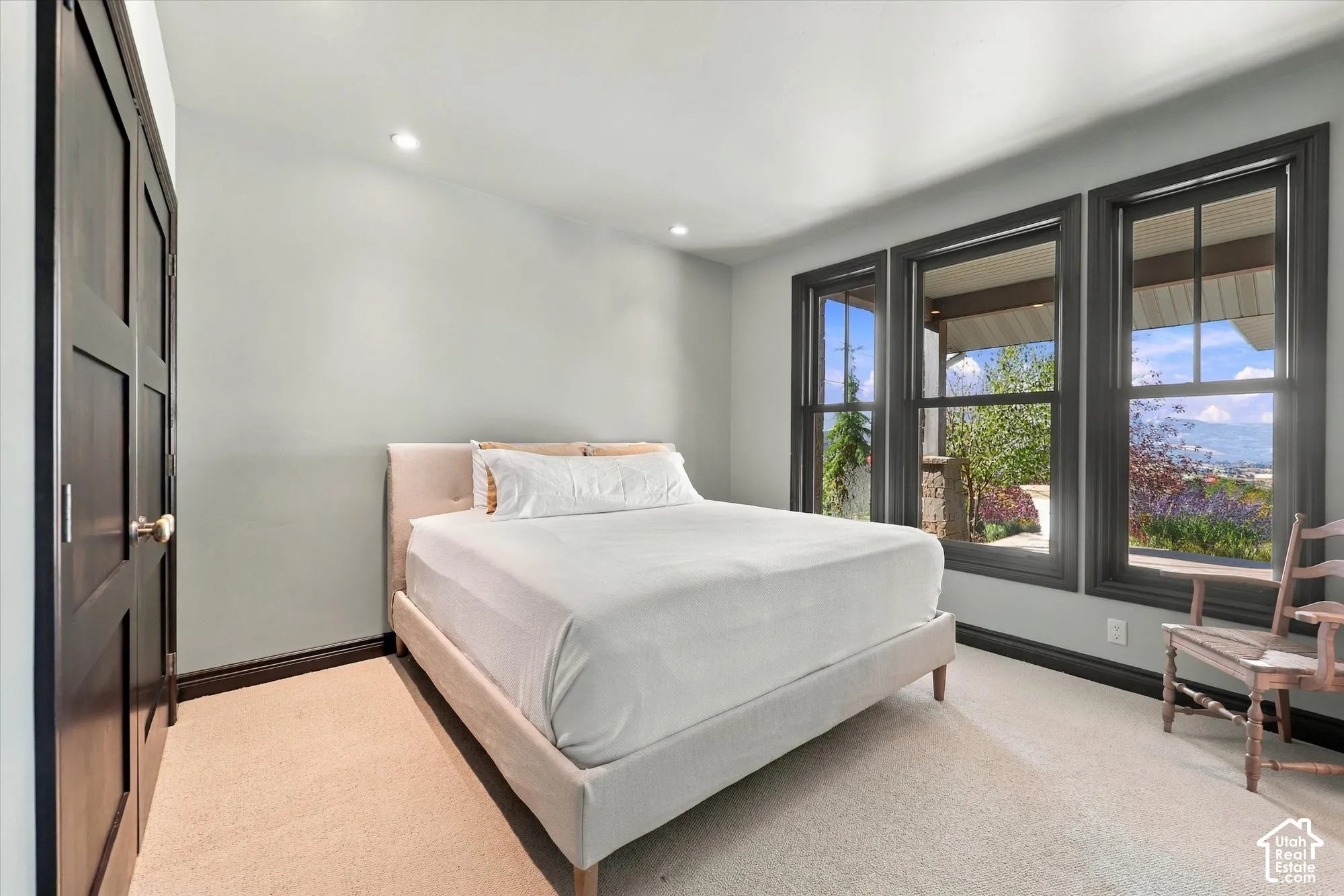 Room featuring neutral carpet, recessed lighting, dark-framed windows, and a set of dark wood-finish paneled doors