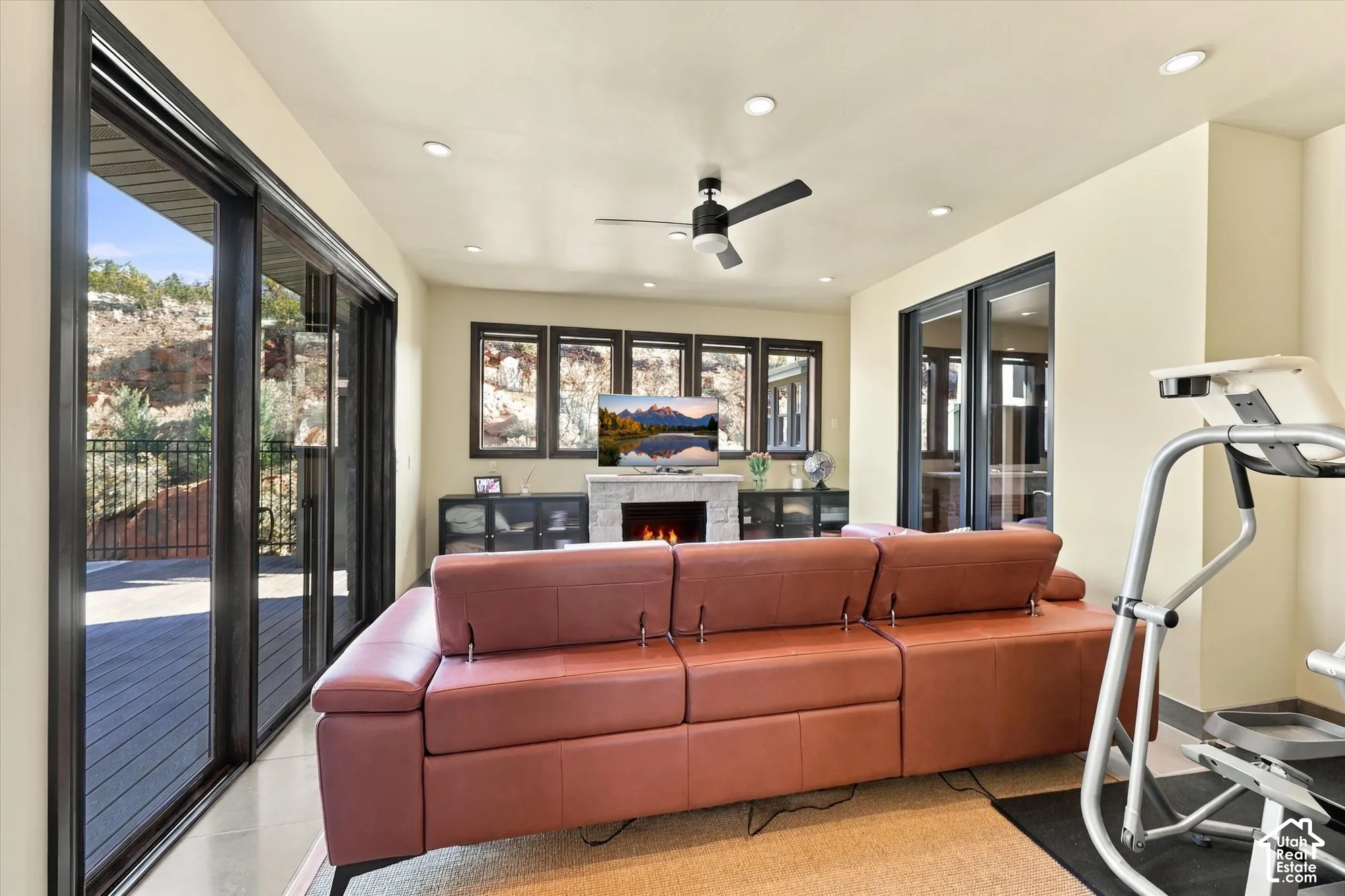 Living area featuring sliding glass doors, a stone-surround fireplace, recessed lighting, and a ceiling fan