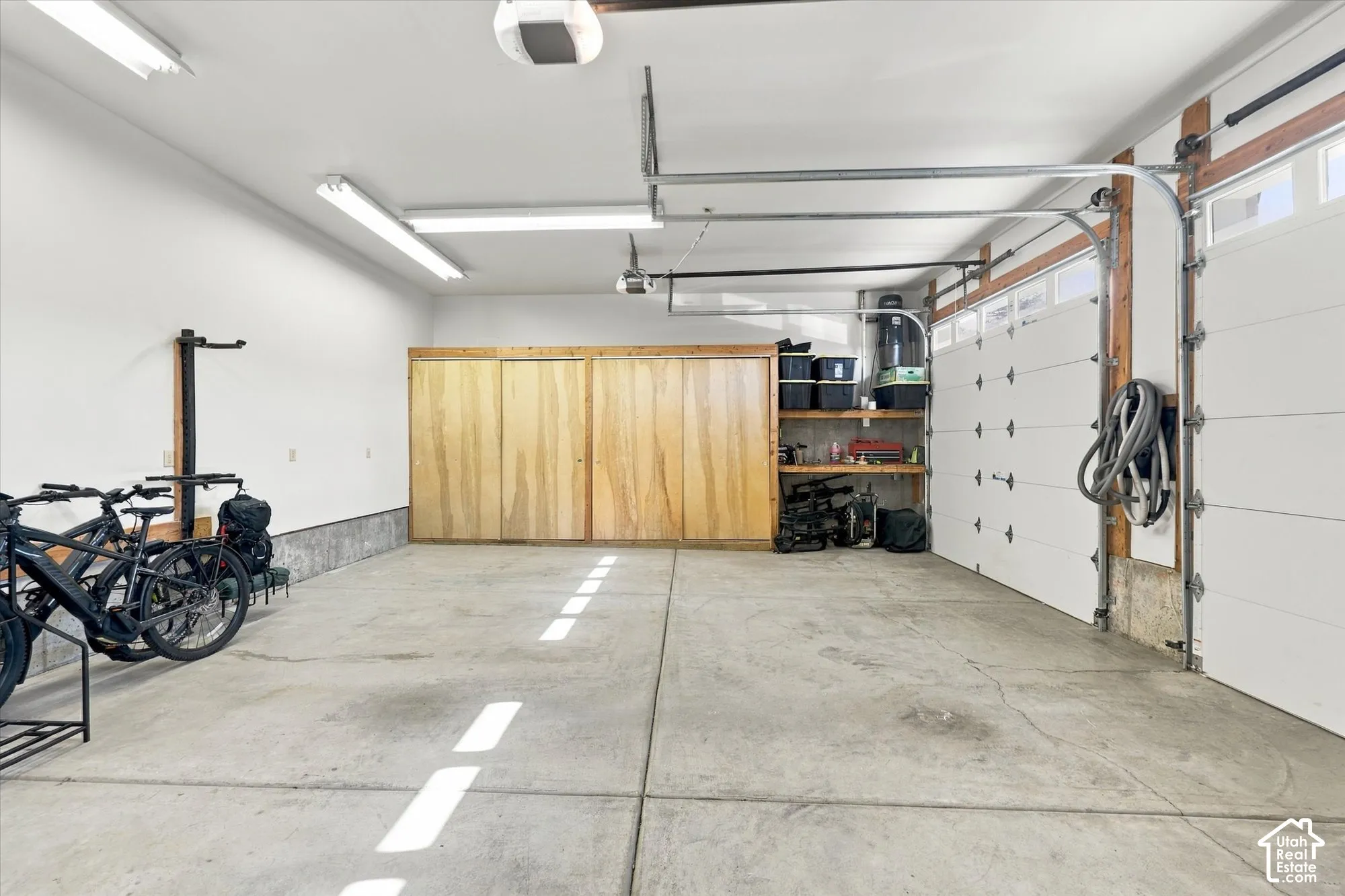 Multi-car garage featuring concrete flooring, built-in wooden storage cabinetry, integrated shelving, and overhead lighting fixtures