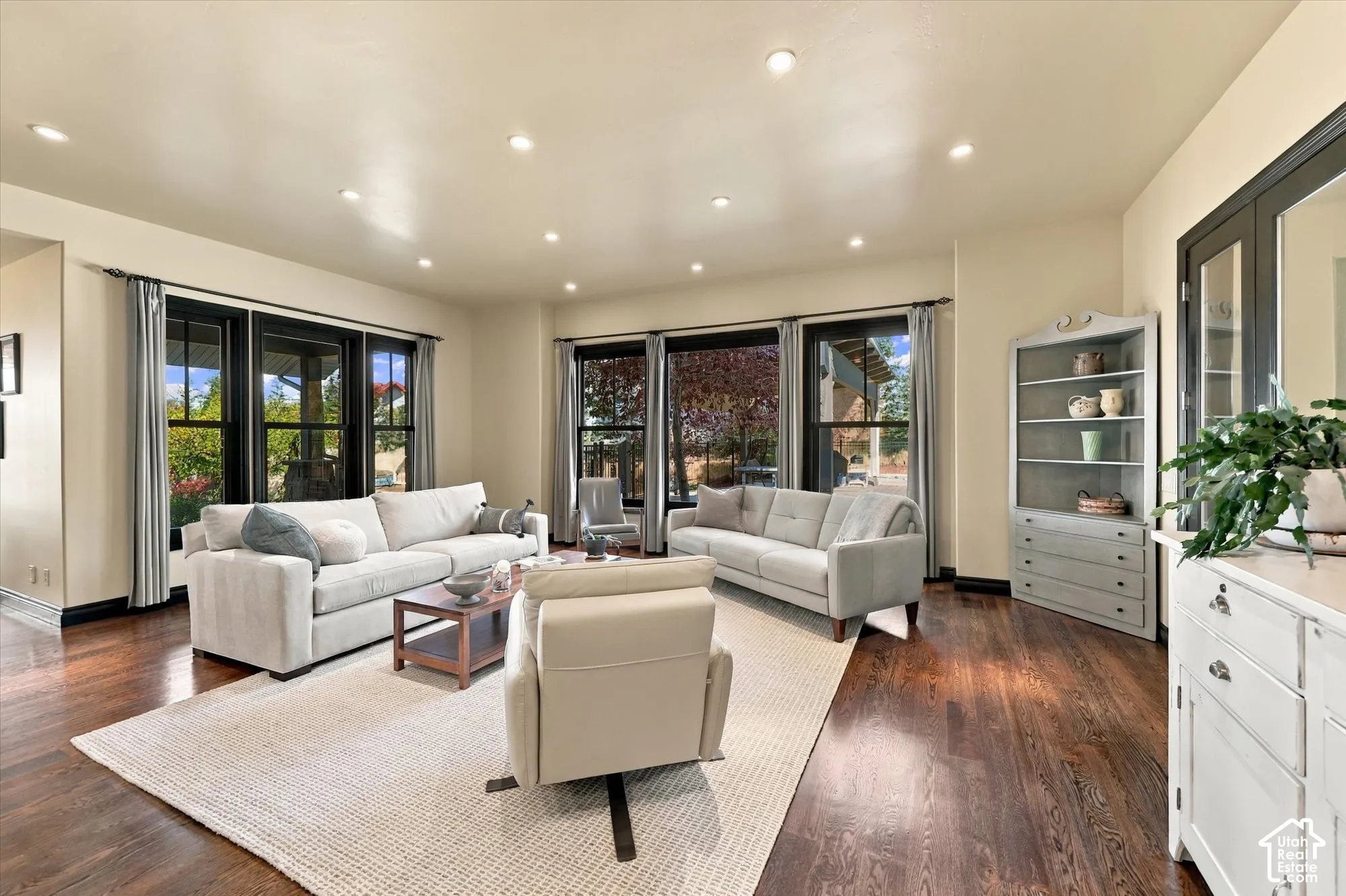 Living area featuring wood-finish flooring, recessed lighting, and large windows with dark-finish frames