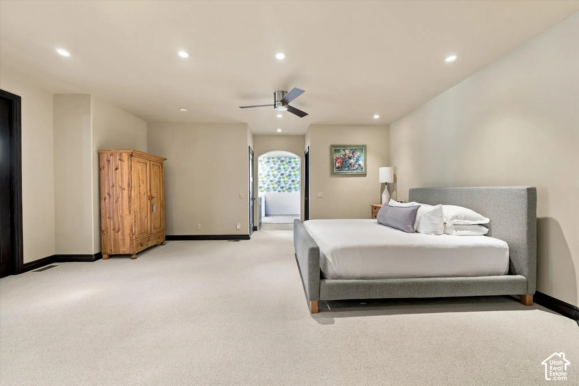 Neutral wall tones, recessed lighting, ceiling fan, carpeted flooring, and an arched doorway