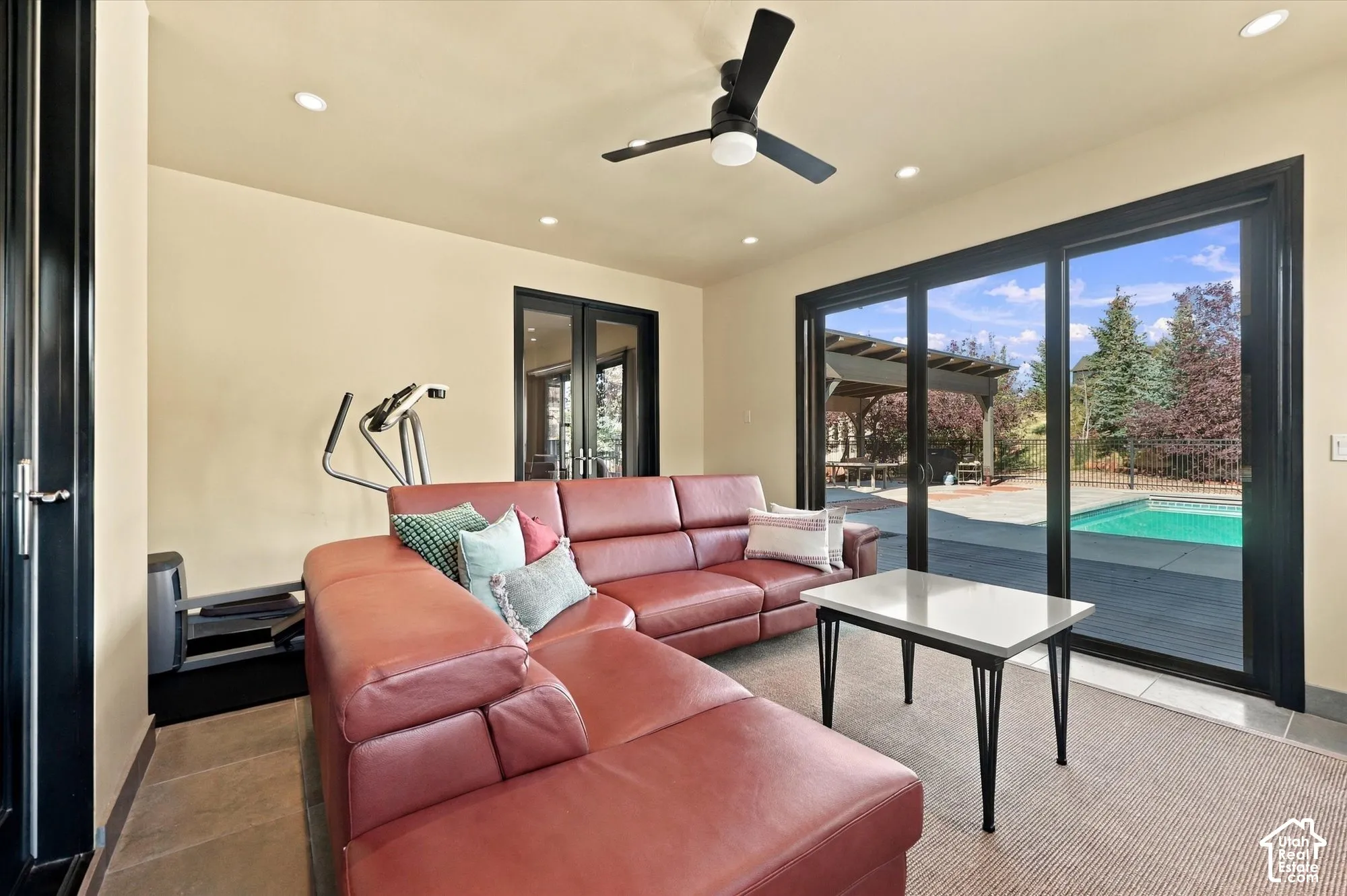 Sunroom featuring tile flooring, a matte black ceiling fan, recessed lighting, and large sliding glass doors opening to an exterior swimming pool and patio area