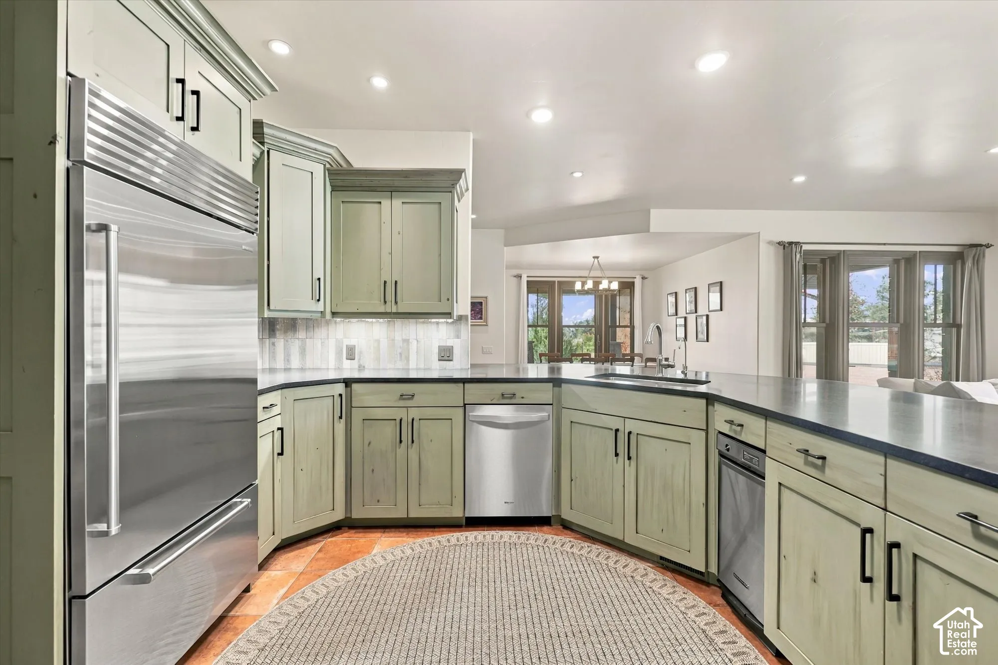 Custom cabinetry with matte black hardware, stainless steel appliances, dark stone-finish countertops, recessed lighting, and tile flooring
