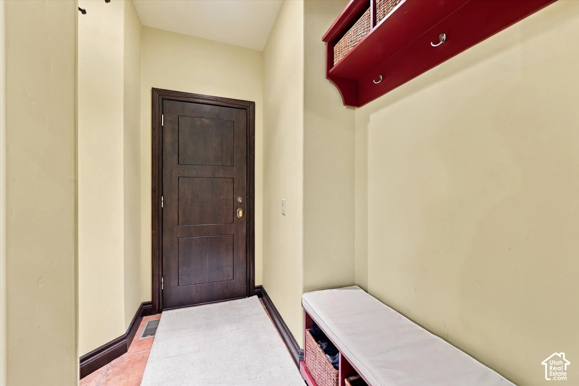 Entryway featuring a dark-stained wood door, wall-mounted storage unit with integrated coat hooks, and built-in bench seating