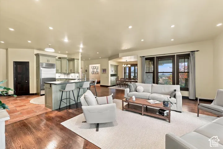 Open-concept area featuring hardwood flooring, recessed lighting, kitchen island with stone countertops, and multi-pane windows with dark trim