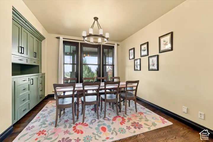 Custom sage green built-in cabinetry, dark wood-finish flooring, oversized multi-pane windows with dark trim, and a contemporary circular chandelier