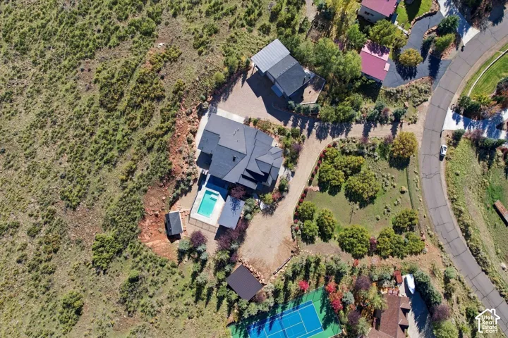 Aerial perspective of a property featuring an in-ground swimming pool, a private tennis court, expansive grounds, and a detached outbuilding