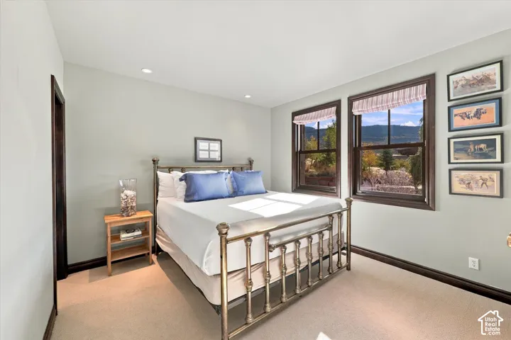 Neutral-toned walls, recessed lighting, carpeted flooring, and double-pane windows with dark wood-finished trim showcasing mountain scenery