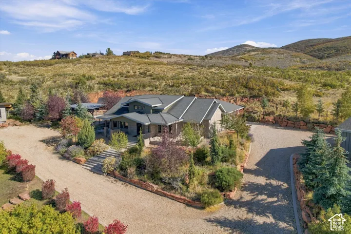 Multi-level architectural exterior featuring stone masonry and shingle roofing, surrounded by tiered natural stone retaining walls and extensive native landscaping