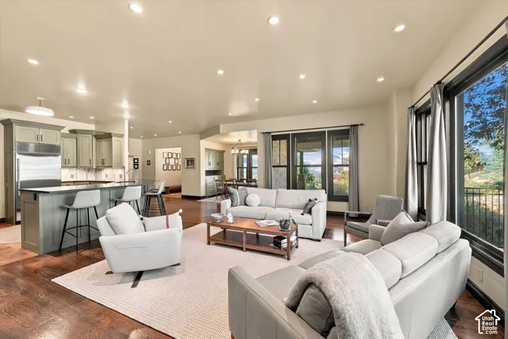 Open-concept living space featuring wood-finish flooring, recessed lighting, a center island with bar seating, custom cabinetry, and large windows with mountain scenery