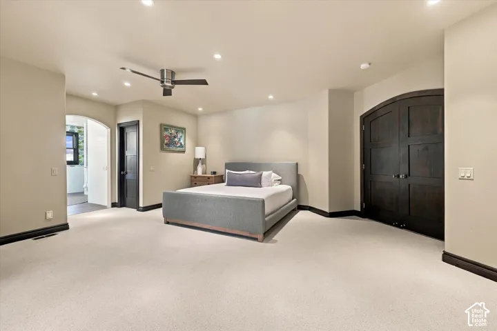 Spacious room featuring arched doorways, recessed lighting, a modern ceiling fan, and dark-stained solid wood doors
