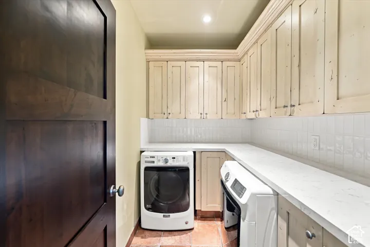 Laundry room featuring custom painted cabinetry, stone-finish countertops, subway tile backsplash, terra-cotta tile flooring, and a solid wood-finish door