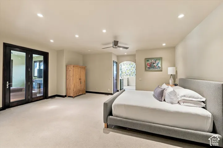 Neutral-toned room featuring recessed ceiling lighting, a brushed metal ceiling fan, carpeted flooring, and dark-stained glass-paned doors