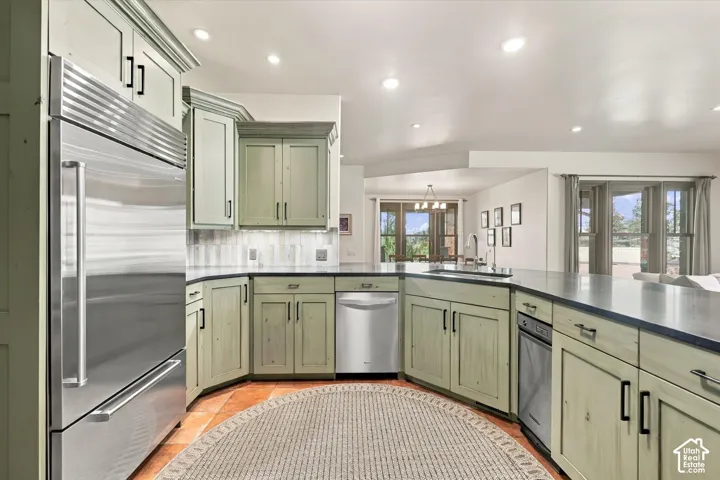 Custom cabinetry with matte black hardware, stainless steel appliances, dark stone-finish countertops, recessed lighting, and tile flooring