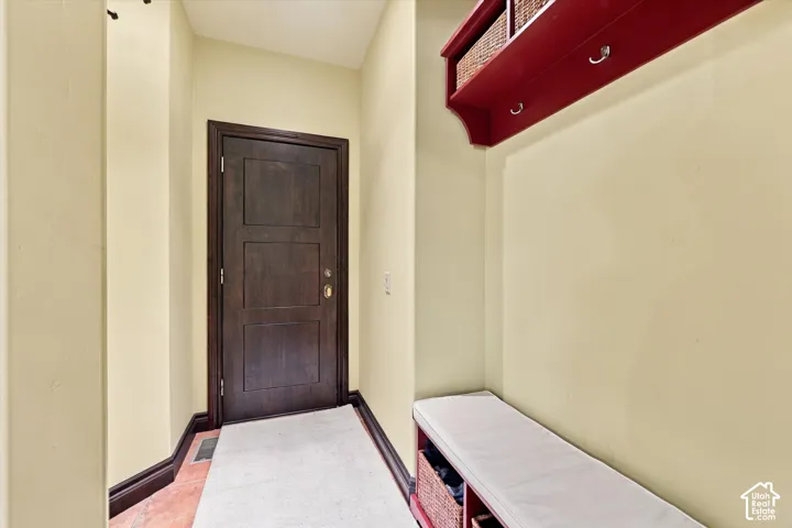 Entryway featuring a dark-stained wood door, wall-mounted storage unit with integrated coat hooks, and built-in bench seating