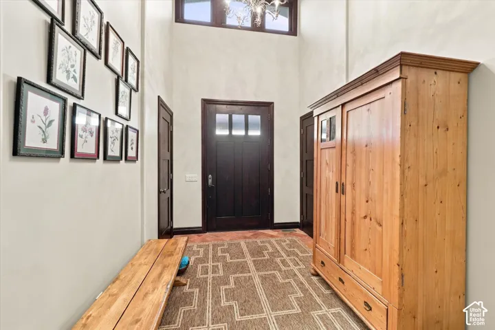 Foyer featuring a high ceiling, transom window, dark-stained solid wood entry door, and stone-finish tile flooring
