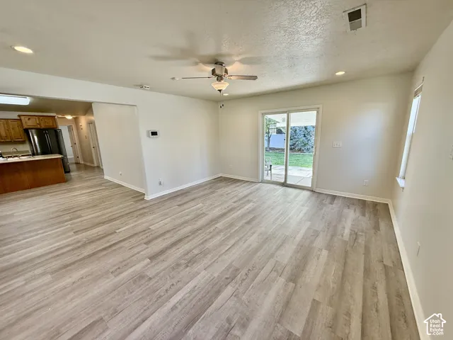 Open floor plan featuring wood-finish flooring, recessed lighting, ceiling fan, and sliding glass doors leading to the exterior