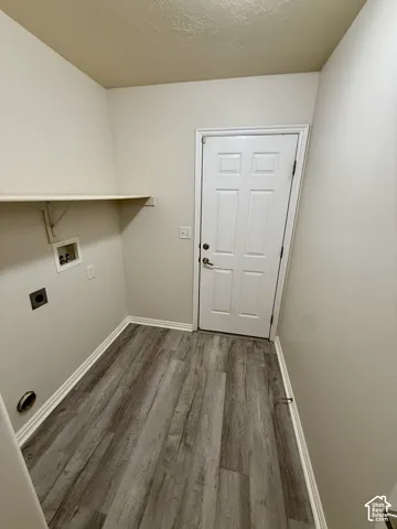 Utility space featuring wood-finish flooring, a six-panel door, and a built-in wall shelf