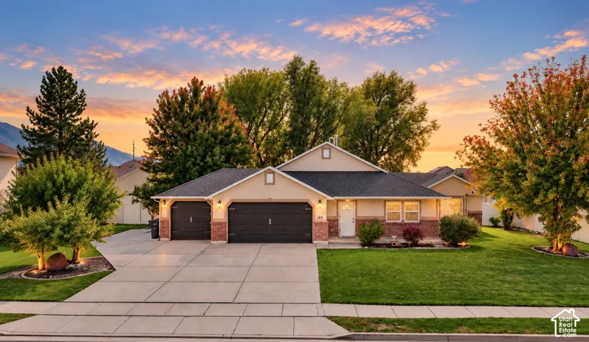 Single-level exterior featuring a brick and stucco facade, an attached three-car garage, and a concrete driveway