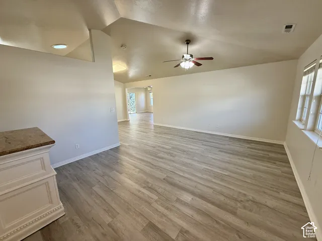 Vaulted ceilings, wood-finish flooring, recessed lighting, and a multi-blade ceiling fan with integrated lighting