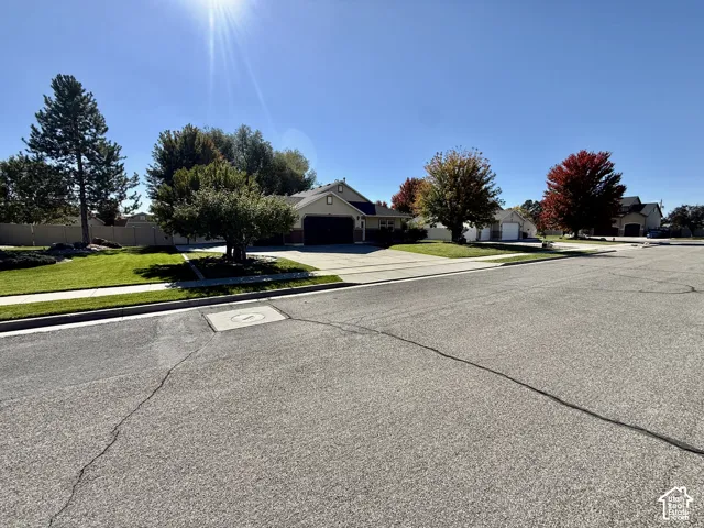 Single-story residence featuring a multi-car garage, concrete driveway, and manicured front lawn with mature landscaping