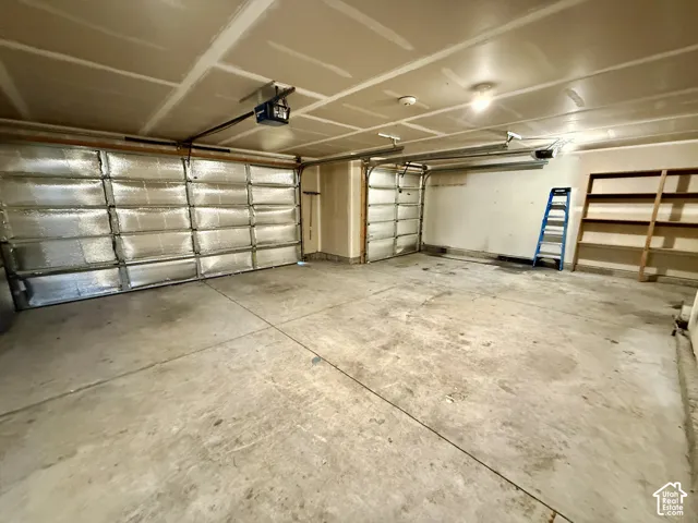 Spacious garage featuring polished concrete flooring, coffered ceiling with recessed lighting, and multiple garage doors with insulated panels