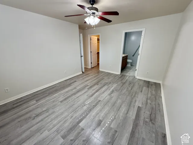 Wood-finish flooring, ceiling fan with integrated lighting, and multiple interior doors featuring panel details