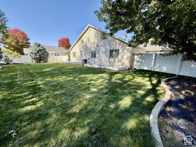 Spacious backyard with mature landscaping and manicured lawn, offering abundant natural light and shade from established trees