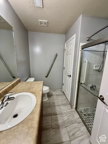 Spa-inspired primary bathroom featuring a wood-finish vanity with an undermount sink, quartz countertop, and oil-rubbed bronze fixtures