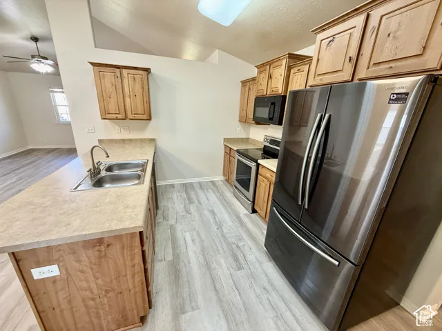 Modern kitchen featuring stainless steel French-door refrigerator, electric range with microwave, and undermount sink with gooseneck faucet