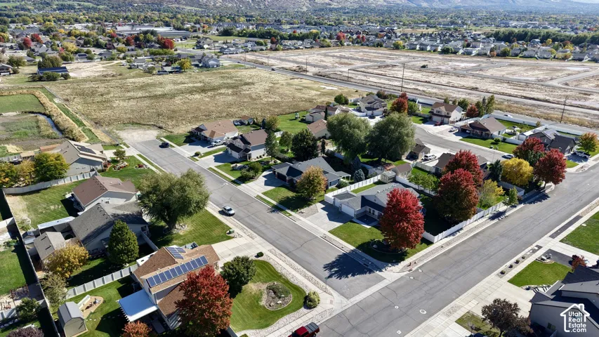 Aerial perspective of a suburban neighborhood featuring residential lots, paved roadways, mature deciduous trees, vinyl fencing, and mountain scenery