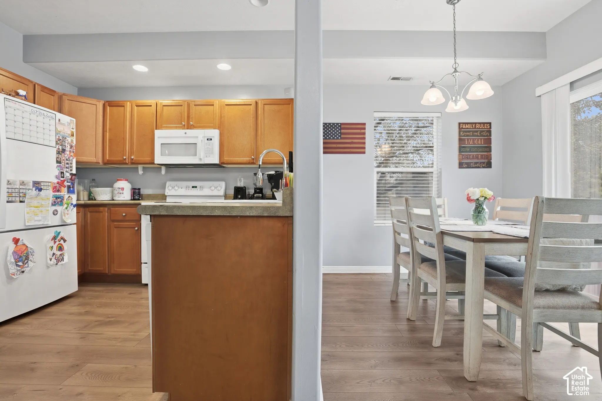 Kitchen featuring wood cabinetry, laminate countertops, a white over-the-range microwave, recessed lighting, and wood-finish flooring