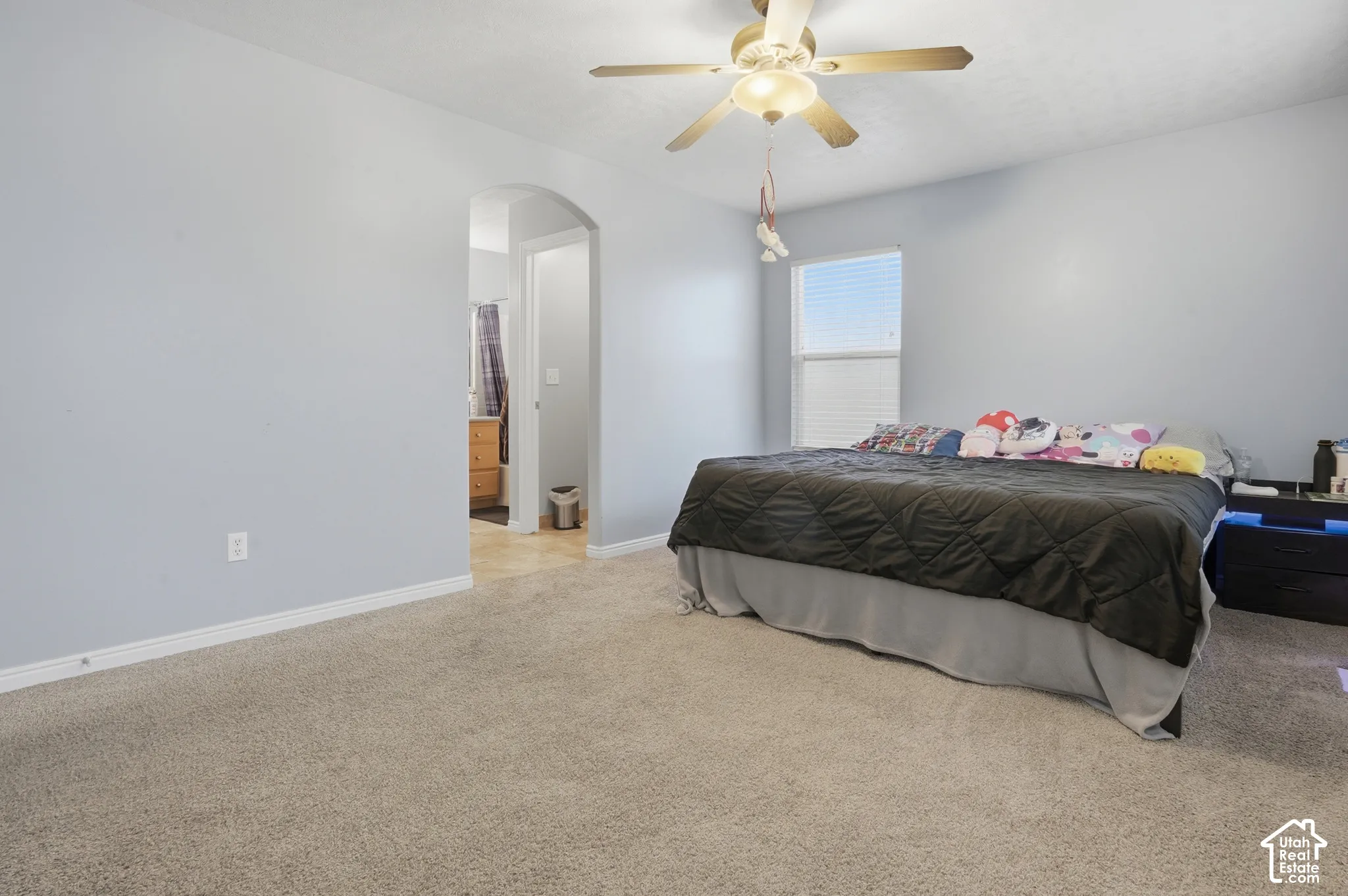 Carpeted flooring, arched doorway, ceiling fan with integrated light fixture, and large single-hung window