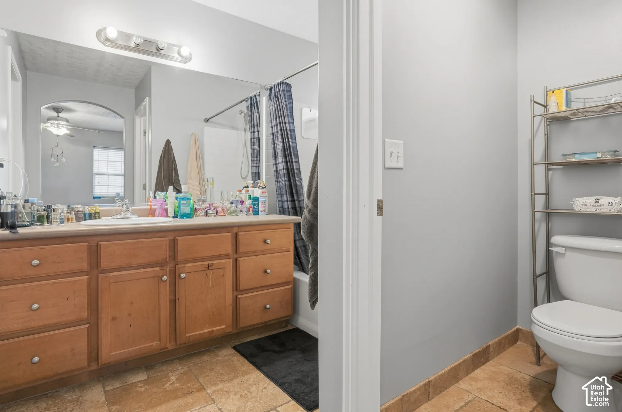 Bathroom featuring a light wood vanity with a solid surface countertop, an expansive wall mirror, a bathtub and shower combination, and tile flooring