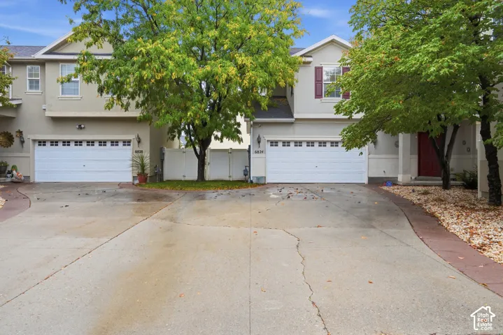Two-story stucco exterior featuring double-car garages, multi-gabled rooflines, and decorative shutter accents