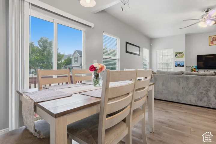 Open-concept space featuring wood-finish flooring, sliding glass door with external deck access, horizontal blinds, and a multi-blade ceiling fan with integrated lighting