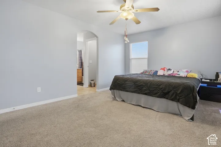 Carpeted flooring, arched doorway, ceiling fan with integrated light fixture, and large single-hung window